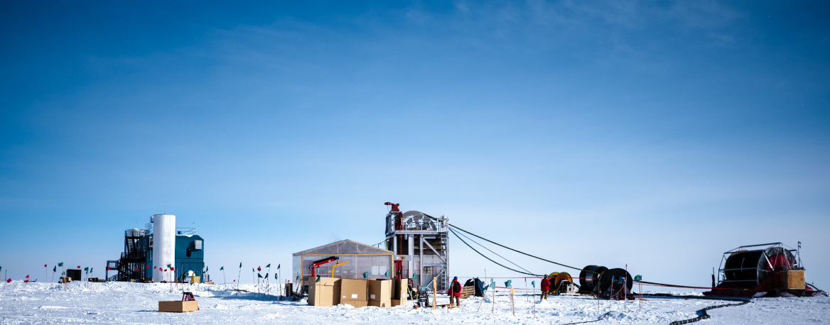 図６ドリル切削と埋設を行う建屋: 掘削孔の位置に設置し、天井から検出器に接続するケーブルを降ろす。左奥にIceCubeのコントロールセンターが見える。(photo: Aya Ishihara/IceHap)